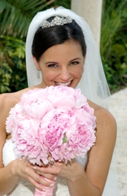 young bride smiling behind pink bridal bouquet