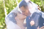 young married couple kiss underneath wedding veil